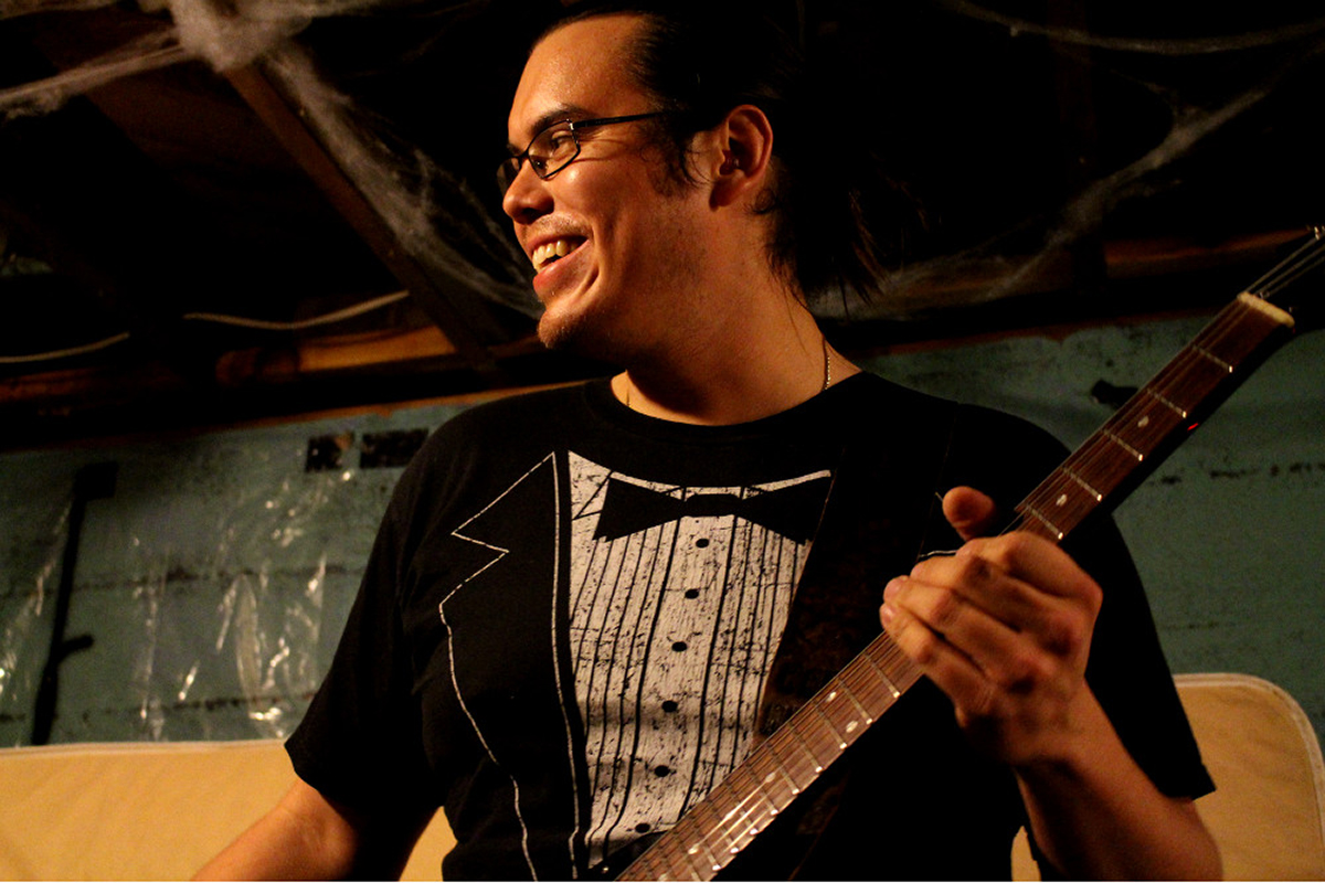 John Gladstone practices heavy metal guitar in his bandmate's basement. He says returning home to Haida Gwaii would mean giving up his musical ambitions